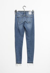 Jeans ajustados de mezclilla azul oscuro, con una cintura alta, dobladillo deshilachado y dos bolsillos traseros. Etiqueta situada en la cintura.