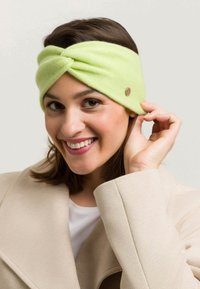 Un bandeau tricoté vert clair avec un design torsadé et un petit bouton décoratif marron. Texture douce avec un ajustement serré.