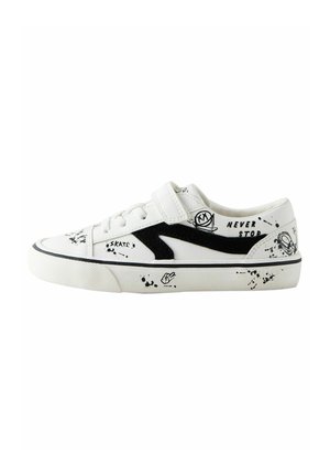 Witte skate schoenen met een zwart suède detail, voorzien van graffiti-stijl geprinte accenten en een klittenbandsluiting over de veters. De tekst bevat "NEVER STOP."