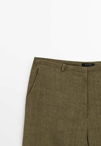 Pantalon taille haute vert olive avec passants pour ceinture et poches latérales, en tissu texturé, visible de la taille jusqu'à mi-cuisse.