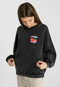Sweatshirt noir avec un col rond et une coupe décontractée, arborant un graphique coloré "CHERIES LOVER" sur le devant et un tissu texturé.