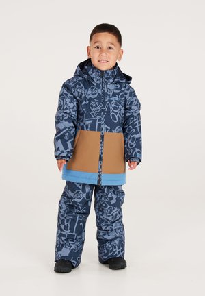 Modrý a hnědým vzorem zdobený snowsuit s krátkou bundou a volnými kalhotami. Má kapuci, elastické manžety a solidní modrý akcent.