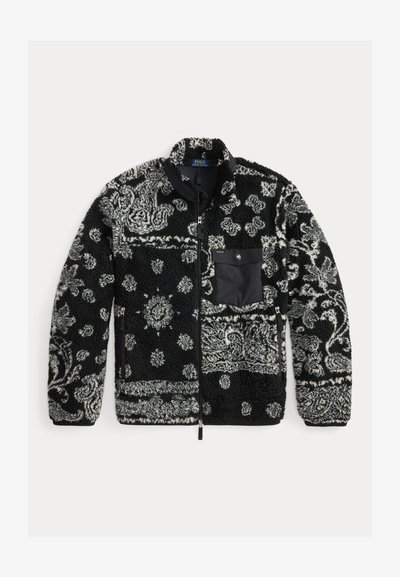 Czarna i szara polarowa kurtka w wzory z zapięciem na zamek, teksturowana tkanina i czarna kieszeń na piersi. Zawiera wirujące i kropkowane wzory.