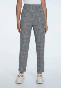 Hoge taille geplooide broek met een zwart-wit geruite print, getailleerde pasvorm en een soepele stoftextuur. Gecombineerd met chunky witte loafers.