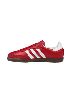Sneaker rossa a profilo basso con strisce bianche, suola marrone, chiusura con lacci e colletto imbottito bianco sul tallone.