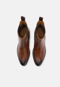 Bottines en cuir marron avec une finition lisse, des panneaux latéraux élastiques et un tirant à l'arrière. Présente un bout pointu et une semelle plate.