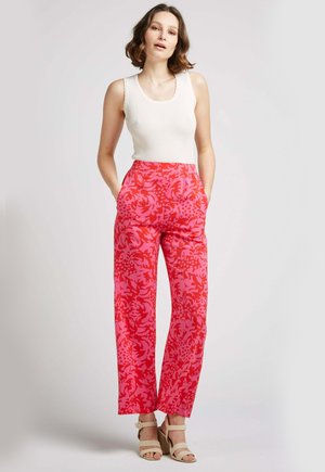 Pantalons larges rose vif avec un motif floral, dotés d'une taille élastique et de poches latérales. Assortie à un débardeur blanc à côtes.