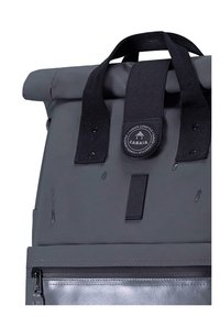 Zaino grigio a roll-top realizzato in materiale impermeabile, con spallacci neri, un logo circolare e una tasca frontale con cerniera dotata di un interno argento.
