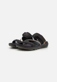 Mustad sussid, millel on lame tald, rihmad riidest detailidega ja reguleeritavad Velcro kinnitused. Tekstuuriga materjal koos minimalistliku stiiliga.
