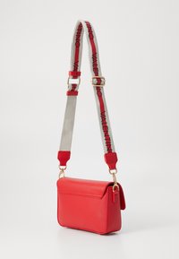Borsa a tracolla rossa in pelle con chiusura a pattina e tracolla rimovibile con la scritta "Valentino" in rosso su sfondo grigio. Accenti in hardware dorato.