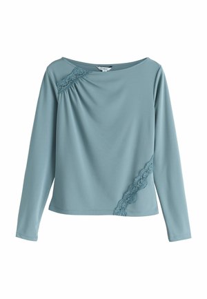 Blusa blu a maniche lunghe con scollo a barca, caratterizzata da dettagli in pizzo sulla spalla sinistra e sul lato inferiore destro.