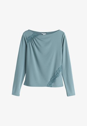 Blusa blu a maniche lunghe con scollo a barca, caratterizzata da dettagli in pizzo sulla spalla sinistra e sul lato inferiore destro.