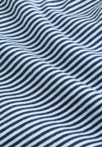 Close-up af blødt stof med jævnt placerede, mørkeblå og hvide vandrette striber, der danner bløde folder.