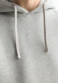 Grijze hoodie met een zachte textuur, voorzien van een voorzak, trekkoordsluitingen in een lichtere tint, en een losse pasvorm.