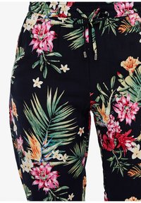 Svarta blommiga byxor med livfulla rosa blommor, gröna blad och dragsko i midjan med metallaccenter. Slät, lättvikts tyg.