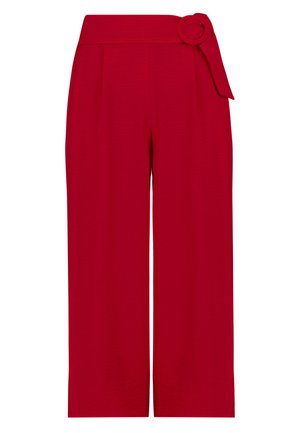 Czerwone spodnie z szerokimi nogawkami i wysokim stanem, z materiałowym paskiem z okrągłą klamrą po prawej stronie.