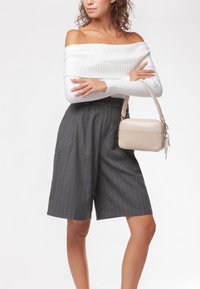 Top blanco acanalado sin hombros, pantalones cortos de pierna ancha a rayas gris oscuro, y un bolso beige claro con asa corta y cremallera.