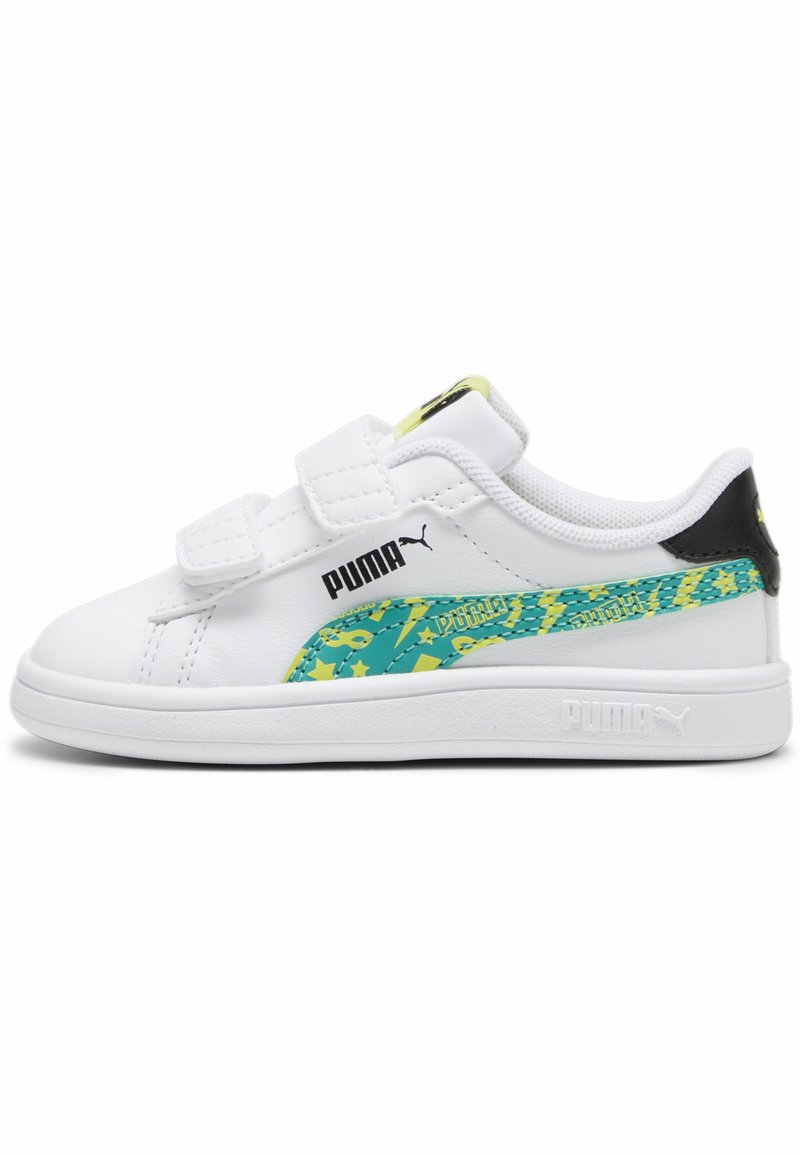 Baskets blanches de sport avec des bandes velcro, dotées d'un accent à motifs verts et jaunes sur le côté et d'un détail de talon noir.