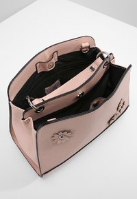 Rosa läderhandväska med texturerad yta, svart inredning, blommiga accenter och flera fack. Har tryckknappslås och cirkulär hårdvara.