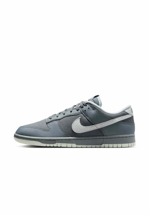Grå Nike lavtop sneakers med hvid swoosh-logo, snørebånd og lys grå sål, vist fra siden på hvid baggrund.