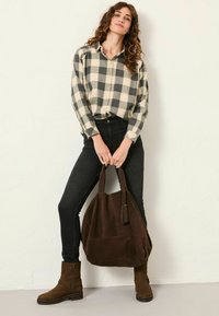 Black and cream checkered button-up shirt, black jeans, brown suede ankle boots, and a large brown suede handbag with a tassel detail.