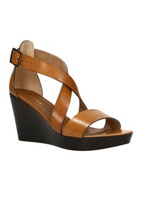 Sandales à plateformes en cuir marron avec un bout ouvert et un design à lanières croisées. Le talon est épais et foncé, offrant une bonne stabilité.