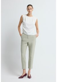 Hvid ærmeløs top, lysegrøn skræddersyede bukser og burgunder højhælede sko. Glat stof, lige snit, afslappet pasform og synlige sidelommer.