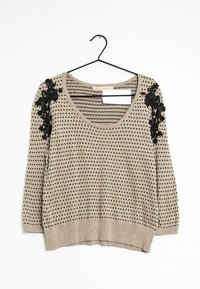 Maglione beige con pois neri e ricamo floreale sulla spalla. Presenta un collo a barca e maniche a tre quarti.
