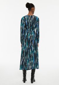 Vestido ajustado de manga larga con un patrón multicolor en azul, verde y negro, con un cinturón en la cintura y un bajo ligeramente acampanado.