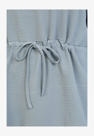 Prenda de color azul claro con cintura fruncida y una cinta de tela. La textura parece suave y ligeramente arrugada, lo que resalta un diseño casual.