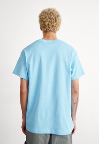 Ljusblå bomullströja med korta ärmar, rundad halsringning och avslappnad passform. Skräddarsydd för komfort, med mjuk textur och minimala detaljer.