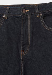 Zone de taille de jean en denim bleu foncé avec surpiqûres contrastées orange, fermeture par bouton, passants de ceinture et poches avant visibles.
