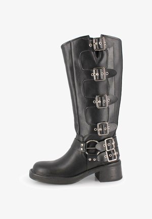 Bota de piel negra hasta la pantorrilla con cinco hebillas y correas plateadas, punta redonda, tacón bajo apilado y detalle decorativo de anillo en el tobillo.