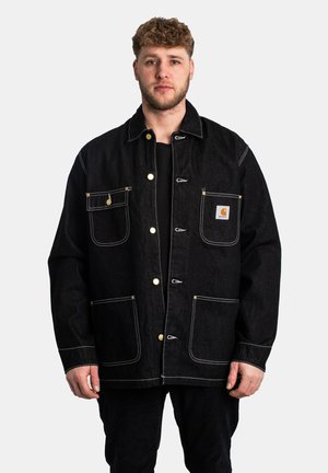 Veste en denim noire avec des accents jaunes, grandes poches avant et coutures blanches contrastées. Dispose de boutons-pression et d'un design à coupe décontractée.