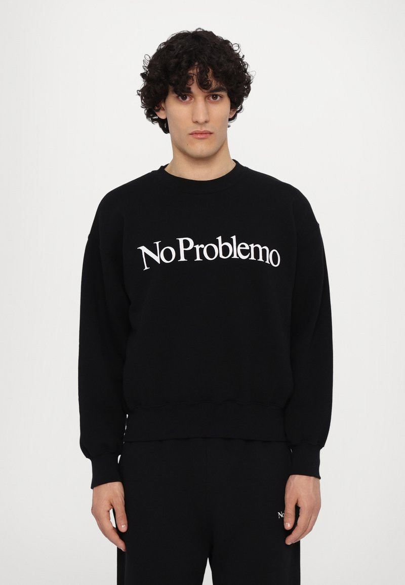 Sudadera negra de algodón con mangas largas, puños y cinturilla acanalados. Presenta el texto blanco "No Problemo" en la parte frontal.