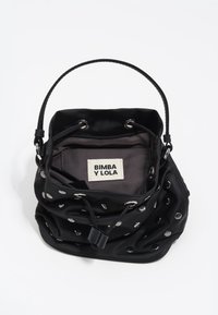 Bolso tipo cubo de tela negra con detalles de ojales plateados, cierre de cordón y un asa corta. El interior cuenta con una etiqueta y forro oscuro.