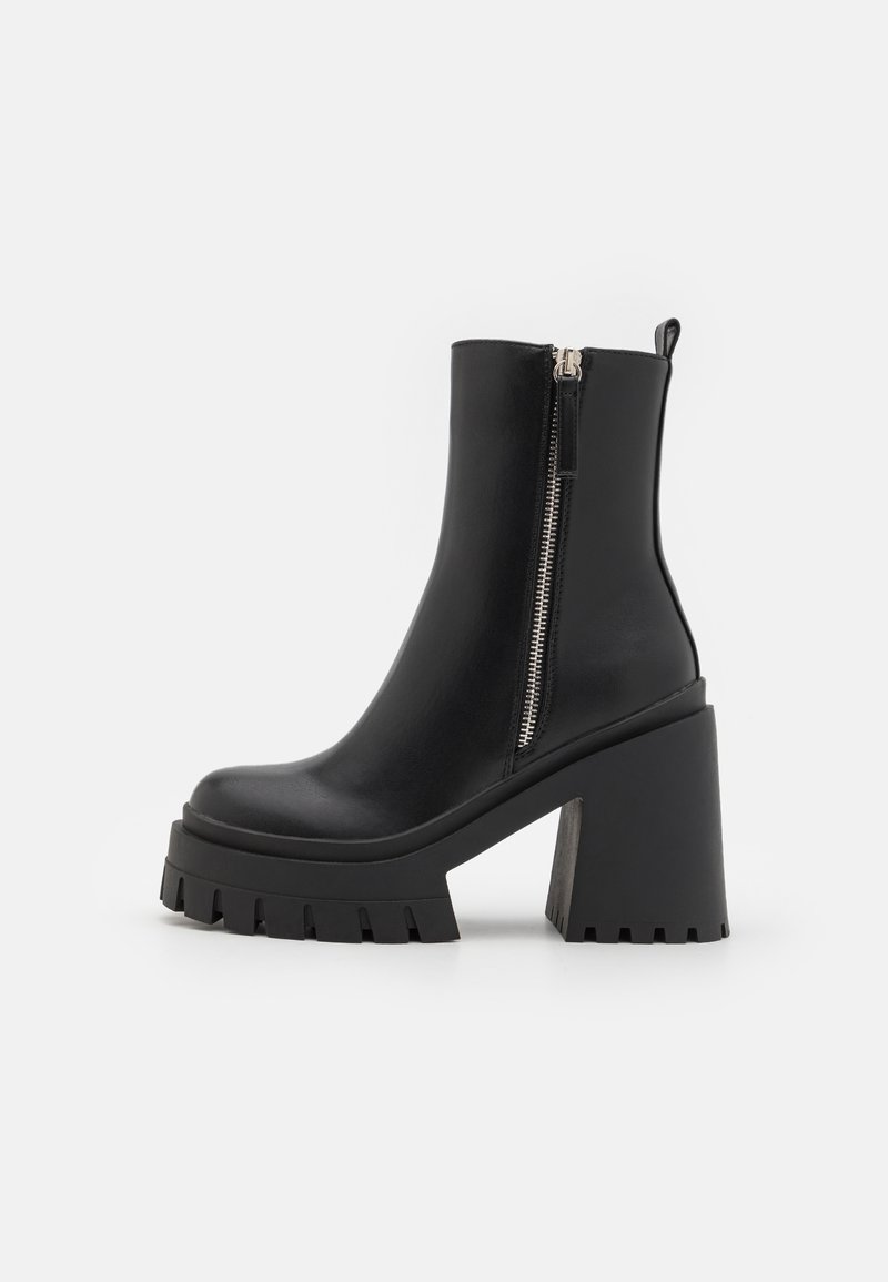 Bottines noires à talons, en cuir lisse, avec une semelle épaisse et un haut talon block, dotées d'une fermeture éclair et d'une languette pour un enfilage facile.