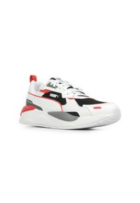 Sneaker atletica bianca con accenti neri e rossi, dotata di upper in mesh testurizzato, suola ammortizzata e un marchio prominente sul lato.