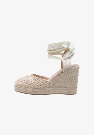 Sandale espadrille à semelle compensée beige en corde tressée, broderie florale sur l\'avant-pied, et liens à nouer autour de la cheville en tissu sous forme de nœud.