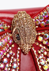 Borsa a pochette rossa con una chiusura metallica dorata a forma di mano, decorata con strass scintillanti e paillettes colorate. Dettagli in tessuto texturizzato.