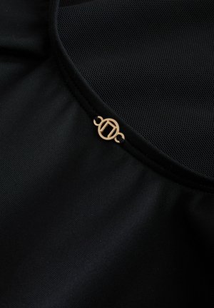 Schwarzer Stoff mit einer strukturierten Mesh-Überlage, versehen mit einem goldenen, runden Logo-Akzent am Ausschnitt. Glatte Oberfläche mit subtiler Schimmer.