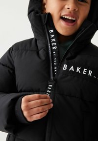 Čierna puffová bunda so zipsom vpredu a so značkovým ťahákom, veľkým textovým logom "BAKER" na hrudi a fleecovými podšívkami vrecka.