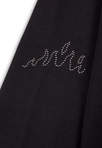 Tejido negro con un diseño curvado de pequeños remaches plateados dispuestos en un patrón de ondas, creando un acento texturizado en la superficie.