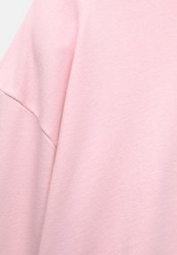 Tessuto rosa chiaro con una superficie strutturata, che mostra un morbido motivo a maglia e un design senza cuciture, evidenziando la sua finitura liscia e il colore.