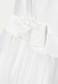 Abito bianco con un corpetto strutturato, un elegante fiocchetto in satin in vita e una gonna in tulle trasparente a strati per maggiore volume e morbidezza.