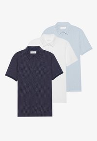 Tres camisetas polo: una azul marino con un patrón de diamantes, una blanca y una azul claro con lunares. Todas tienen cuellos tipo polo y mangas cortas.