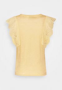 Žlutý top s krátkým rukávem a krajkovým lemem na ramenou, s jemnou texturou a volným střihem. Zobrazeno ze zadní strany.