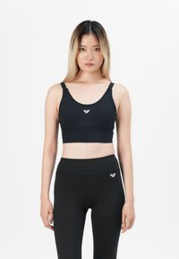Black sports bra with wide straps, rounded neckline, and a centered logo on the front; paired with high-waisted black leggings.