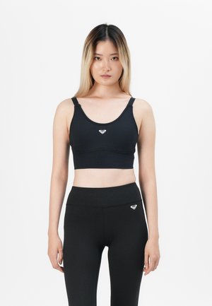 Black sports bra with wide straps, rounded neckline, and a centered logo on the front; paired with high-waisted black leggings.