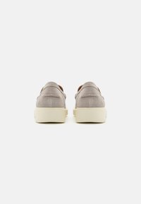 Pantofi slip-on gri din suede, cu o textură moale și o talpă solidă din cauciuc bej, având o cusătură simplă și un spate rotunjit.